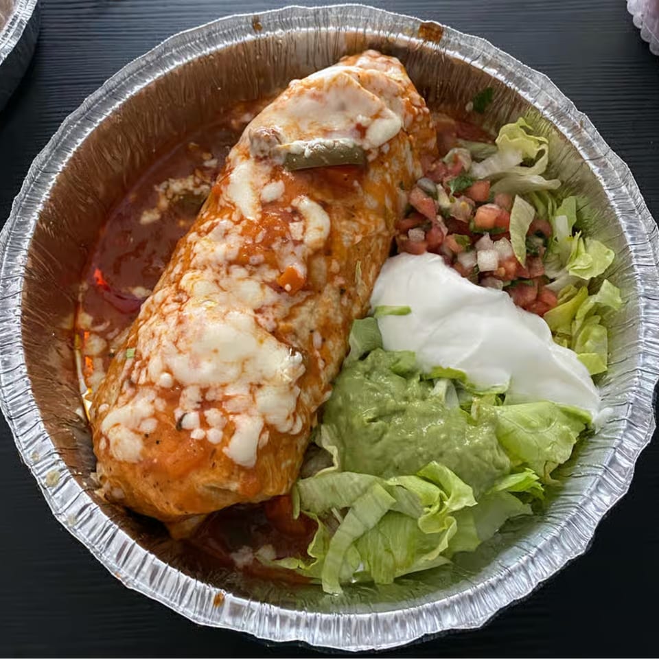 La Casita's wet burrito, topped with melted cheese and sauce, served with lettuce, guacamole, sour cream, and pico de gallo.