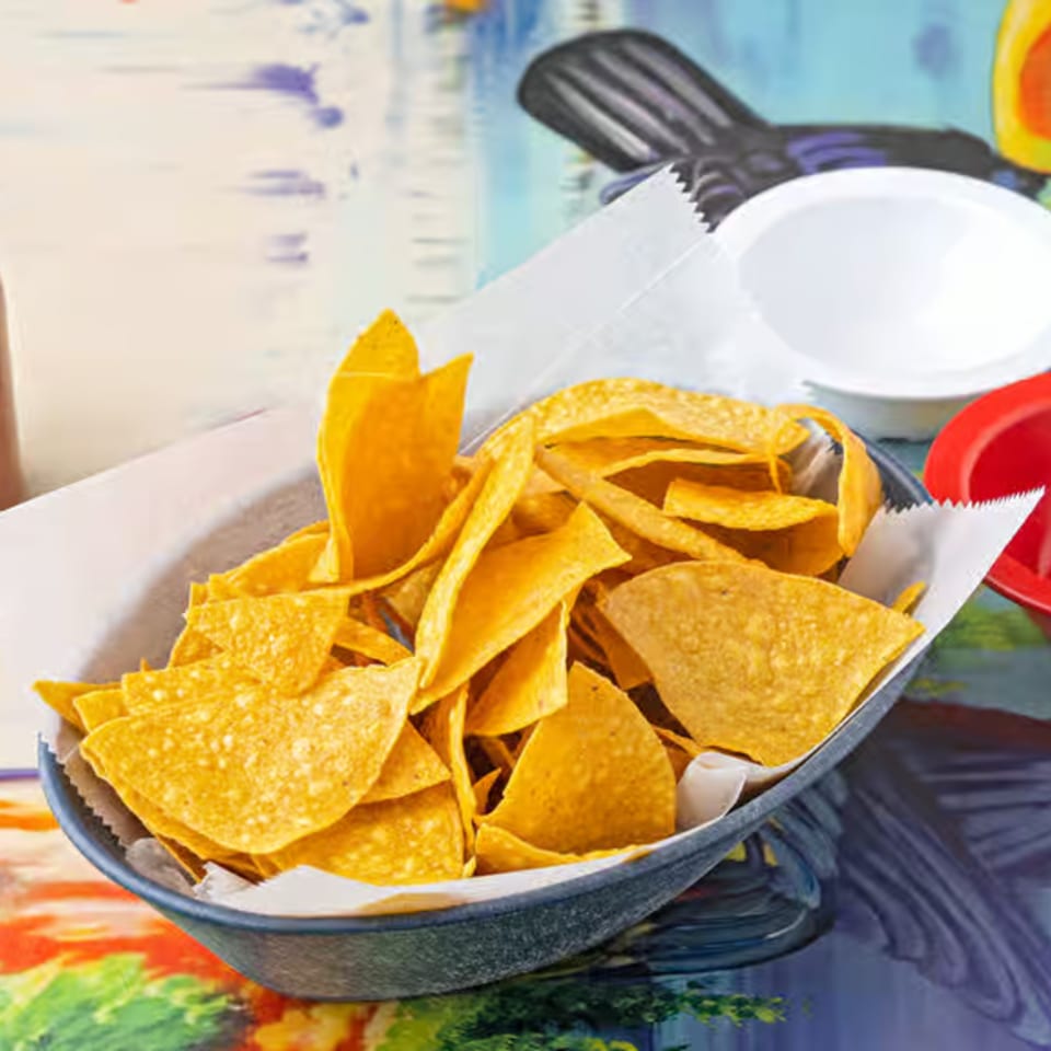 A black bowl filled with crispy, golden tortilla chips on a colorful table at La Casita.