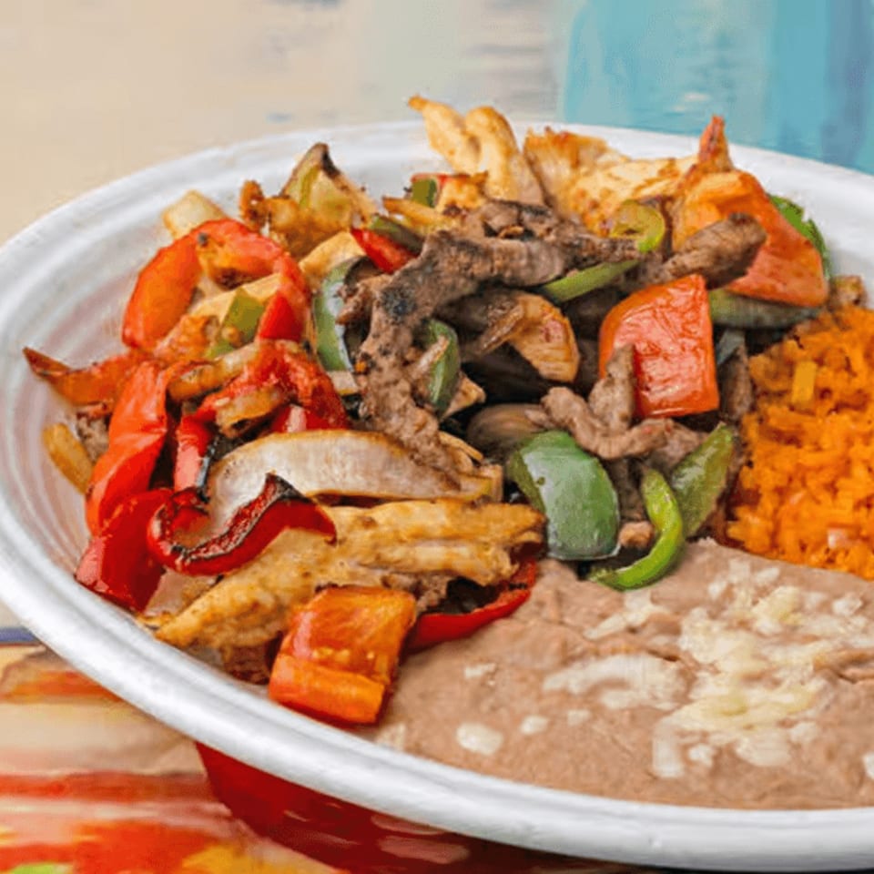 La Casita's fajita bowl with steak, chicken, peppers, onions, rice, and refried beans.