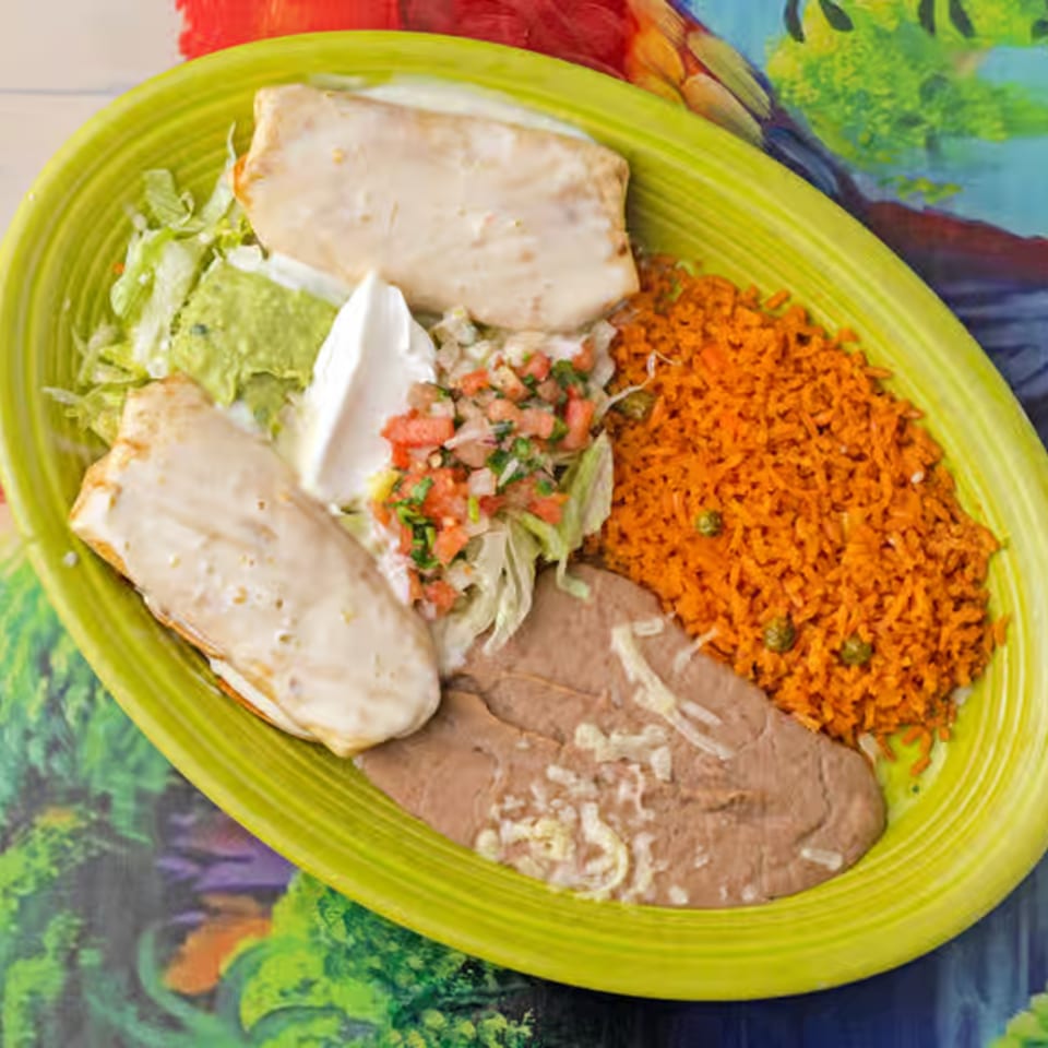 Two burritos with sour cream, guacamole, pico de gallo, rice, and refried beans on a lime green plate.